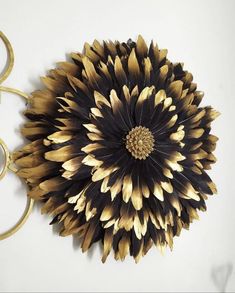 a large black and gold flower sitting on top of a white table next to scissors