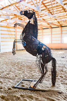 a metal horse is standing in the sand