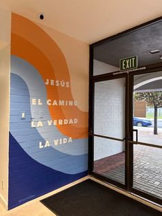 an exit sign in front of a wall with words painted on it that say jesus, el camino, la verdaad, la via