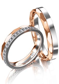 two wedding bands with diamonds on each side and one diamond in the middle, set against a white background