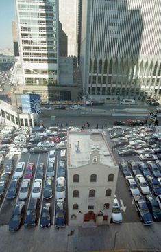 an aerial view of a parking lot with cars parked in the lot and tall buildings