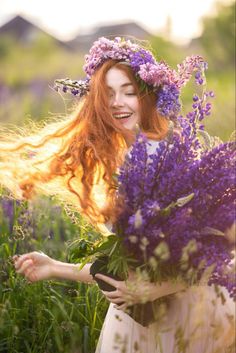 a woman with long red hair holding purple flowers