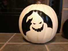 a white pumpkin with a black and white design on it's face sitting on a tile floor