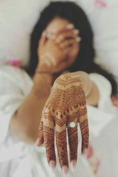 a woman laying in bed with her hand on her face and arm covered by henna