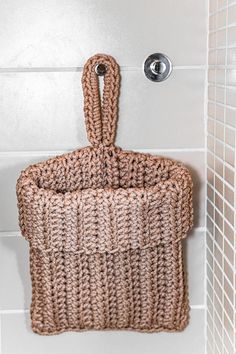 a woven basket hanging on the wall next to a shower faucet in a bathroom