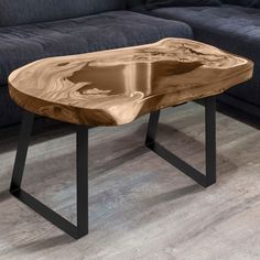 a wooden table sitting on top of a hard wood floor next to a black couch