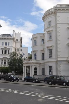 cars are parked on the side of the road in front of white buildings with balconies