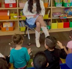 a woman sitting on top of a chair in front of children