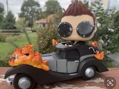 a figurine is sitting on top of a toy car with flames coming out of it