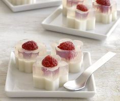 four small desserts with raspberries on them