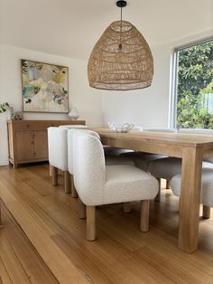 a dining room table with four chairs and a basket hanging from it's ceiling