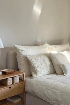 a bed with white linens and pillows in a small room next to a window