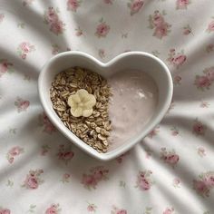 a heart shaped bowl filled with granola and banana slices