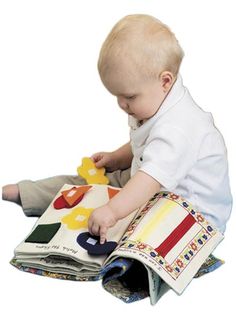 a baby sitting on the floor playing with a book