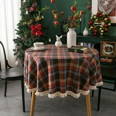 there is a table with a plaid cloth on it and two christmas trees in the background