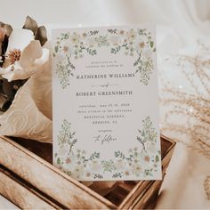 a wedding card with flowers on it sitting in a wooden box