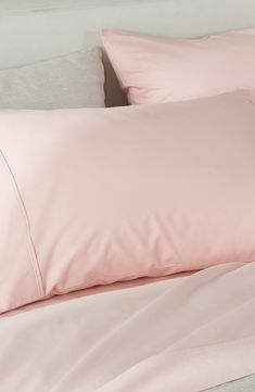 a bed with pink sheets and pillows on it