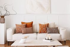 a living room filled with white couches and pillows on top of a wooden table