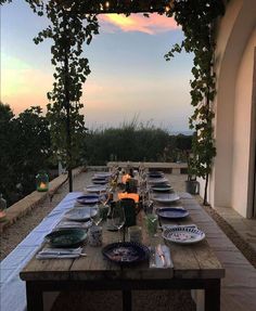 an outdoor dining table set with plates and candles