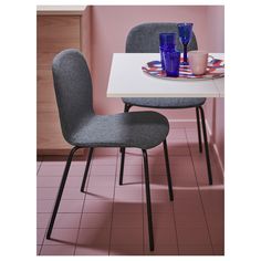 two chairs sitting at a table with plates and cups on it in a pink room