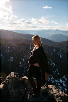 a pregnant woman standing on top of a mountain