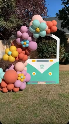 a vw camper decorated with balloons and flowers in front of a house on the lawn