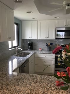 a kitchen with marble counter tops and white cabinets, flowers in the foreground are on the counter