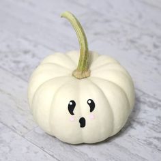 a white pumpkin with a face drawn on it