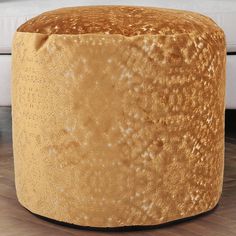 a gold colored stool with white spots on the top and bottom, in front of a couch