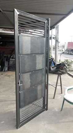 an open metal door sitting on top of a cement floor next to a white table