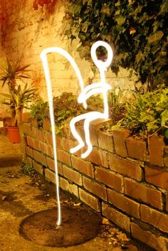 a white light sitting on the side of a brick wall next to a planter