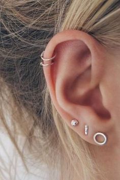 an ear with three different piercings on the top and one is in the middle