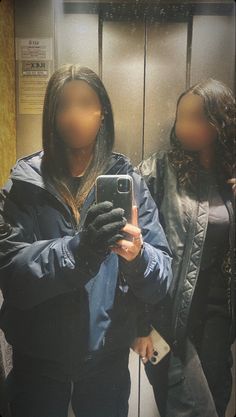 a woman taking a selfie with her cell phone in front of an elevator door