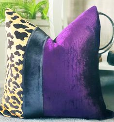 a purple and black pillow sitting on top of a blue carpet next to a potted plant