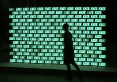 a man is walking in front of a large screen with words on it that are lit up