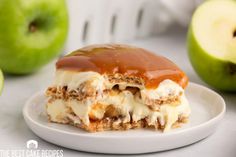 an apple dessert with caramel and ice cream on a white plate next to two green apples