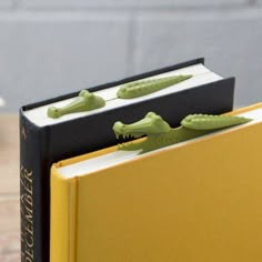 two green alligators are sitting on top of a book