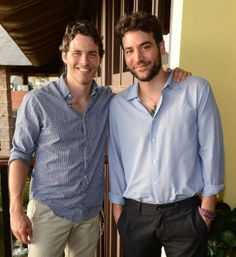 two men standing next to each other in front of a building