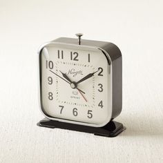 an alarm clock sitting on top of a white table next to a black and silver stand