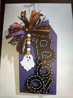 a halloween door hanger with a ghost hanging from it's side and the word boo spelled out