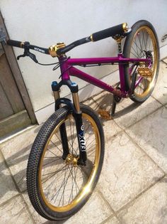 a purple and gold bike parked in front of a building