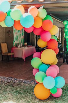 a bunch of balloons that are on the ground in front of a table and chairs