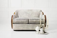 a white couch sitting on top of a white floor next to a cup and saucer