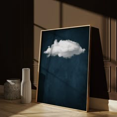 there is a framed photo with a cloud in the sky next to vases and a lamp