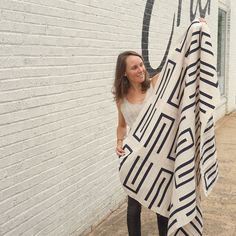 a woman holding up a black and white blanket