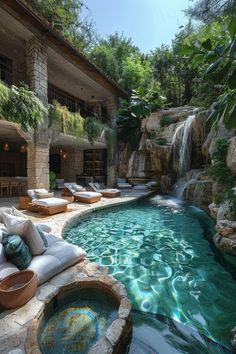 an outdoor swimming pool with lounge chairs and waterfall in the back ground, surrounded by greenery