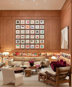 a living room filled with lots of furniture next to a wall mounted book shelf full of books