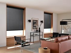 a living room filled with furniture and windows covered in cellular shades on top of them