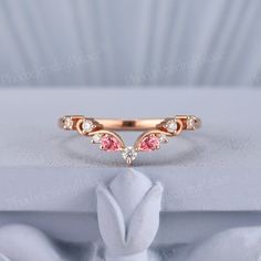 a close up view of a ring with pink stones in it on a white surface