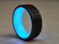 a blue ring with black wheels on it sitting on top of a table in front of a gray background